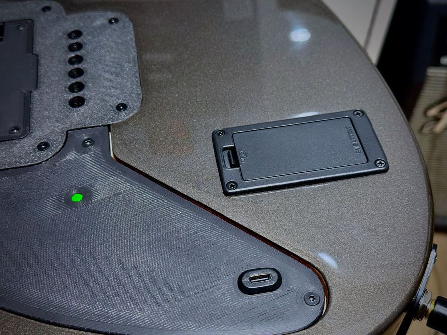 實機拍攝——Filum 琴背面：9V 電池門、USB-C 埠、亮著綠燈的電量指示燈，以及可拆的背蓋子板